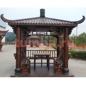 Китайская беседка для дачи с круглыми стойками, резным декором и комплектом деревянной мебели.